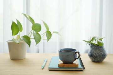 Wall Mural - Blue coffee cup and white flower in a blue vase and notebooks and plant pot