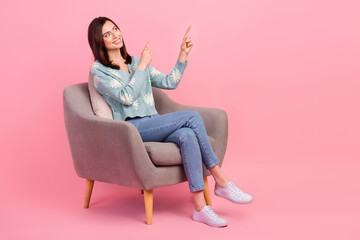 Wall Mural - full body cadre of young satisfied woman sitting grey chair recommend point fingers look empty space