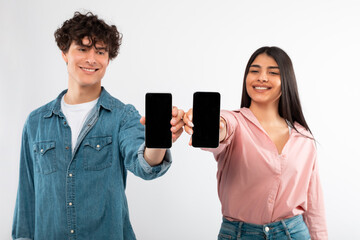 Happy Young Couple Showing Smartphones Displaying Blank Screens, White Background