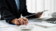 © nBhutinat - Close-up hand of businesswoman’s sitting in the office room and using a calculator to calculate the profit figure.