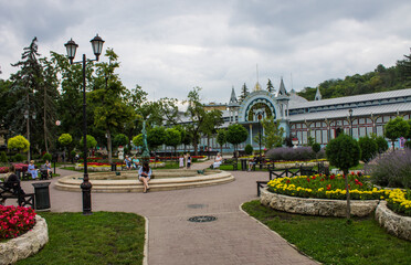 Pyatigorsk, Stavropol Territory, Russia - July, 21, 2022: The blue historical building of the Lermontov Gallery in the flower garden park on a cloudy summer day among green trees and flowerbeds