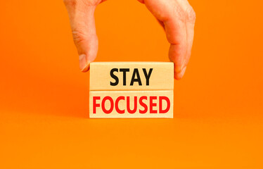 Stay focused symbol. Concept words Stay focused on wooden blocks on a beautiful orange background. Businessman hand. Business, support, motivation, psychological and stay focused concept. Copy space.
