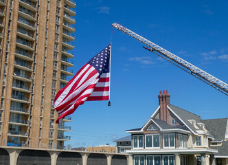 Large American Flag handing from a fire truck ladder weighed down by firefighter boots