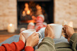 © Clement C/peopleimages.com - Hands, coffee and couple relax by fireplace, bonding and cozy in home together. Tea, man and woman relaxing by fire on Christmas holiday in winter, heat and enjoying quality time with drinks in house