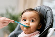 © K.A./peopleimages.com - Cute, sweet and girl baby eating puree for lunch, dinner or snack in her high chair at home. Child development, food and infant kid enjoying a meal with a spoon for growth and wellness in a house.