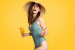 © Prostock-studio - Relax at vacation on beach. Excited woman in swimsuit and straw hat enjoying cocktail, showing peace sign and smiling