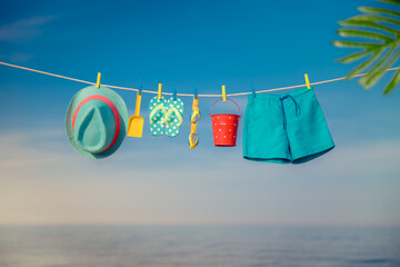 Beach hat, flip-flops and goggles hanging on a clothesline against sea and sky