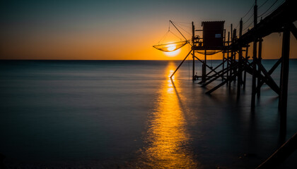 Wall Mural - A fishing hut called carrelet with craft lifting net at sunset. Esnandes, charente maritime, France. The sun is caught in the net.