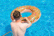 young man with rubber ring in suumer swimming pool 