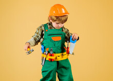 Little Child Boy In Safety Helmet And Toolbelt With Saw And Hammer. Work With Tools. Kid In Builder Uniform With Tool For Repair. Little Repairman, Craftsman Or Foreman Play With Tools For Building.