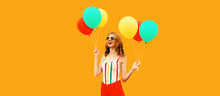 Summer Portrait Of Happy Smiling Young Woman With Bunch Of Colorful Red Yellow Balloons Having Fun Wearing Shorts, Striped T-shirt, Sunglasses On Orange Background