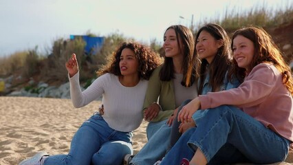 Wall Mural - Four girls sitting on beach.