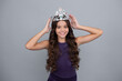 Teenage selfish girl celebrates success victory. Teen child in queen crown isolated on grey background. Princess in tiara. Prom party. Happy girl face, positive and smiling emotions.