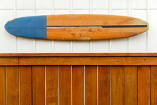 Old Surfboard Mounted On Wall Above Fence.
