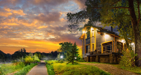 A wooden cottage with a green lawn. Cottage with panoramic windows. Glazing of cottages. Large windows in the house.