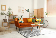 Interior Of Light Living Room With Cozy Brown Sofa And Narcissus Flowers On Coffee Table
