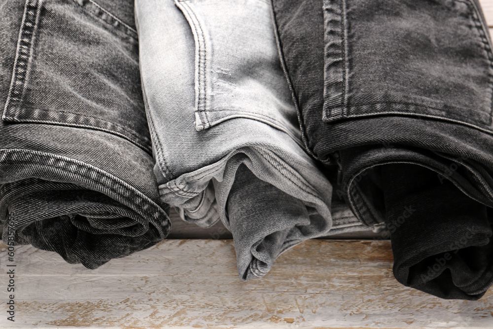 Different rolled denim jeans on wooden background
