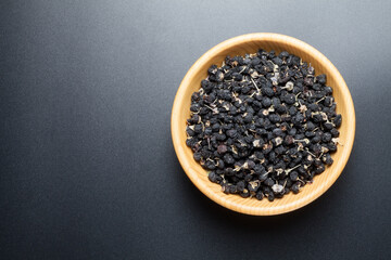 Wall Mural - black Chinese wolfberry in a wooden bowl. top view.