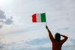© nicoletaionescu - Woman Waving Italian Flag Looking at the Sky. Optimistic girl holding national flag celebrating citizenship