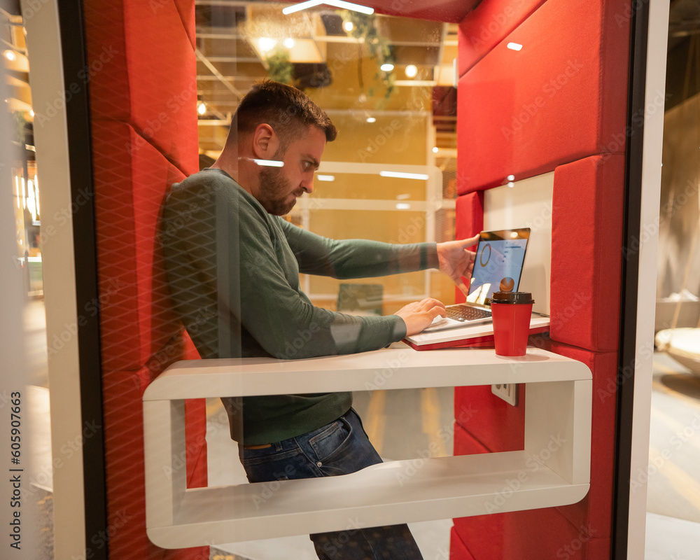 A bearded man in a booth for online negotiations. Privacy booth.