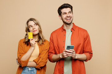 Wall Mural - Young couple two friends family man woman wear casual clothes using mobile cell phone credit bank card shopping online order delivery booking tour together isolated on pastel plain beige background.