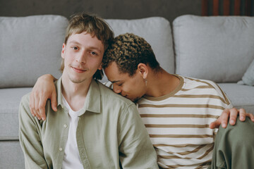 Wall Mural - Close up young happy couple two gay men wear casual clothes together hug kiss shoulder sit on sofa couch at home flat rest spend free spare time in living room Pride day june month love lgbtq concept