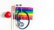 © Verin - stethoscope on lgbtq rainbow flags pride symbol and red heart isolated on white background with copy space, concept of medical care in lgbtq people or diverse genders