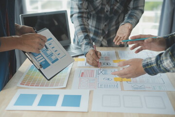 Close up ux developer and ui designer brainstorming about mobile app interface wireframe design on table with customer breif and color code at modern office.Creative digital development agency