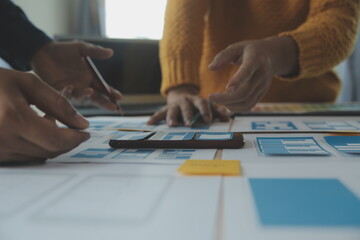 Close up ux developer and ui designer brainstorming about mobile app interface wireframe design on table with customer breif and color code at modern office.Creative digital development agency