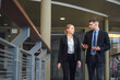 © เลิศลักษณ์ ทิพชัย - Attractive young business man and business woman Talking while walking in the office business conversation working together in the office