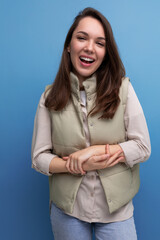 Canvas Print - smiling pleasant european brunette young lady in vest and shirt on studio background