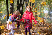 Happy Children Play In The Autumn Park On A Warm Sunny Autumn Day.