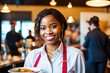 © Pictures Paradise - Portrait of smiling african american waitress in elegant restaurant looking at camera with bokeh background.