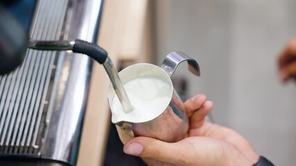 Wall Mural - Closeup of a person pouring milk for making coffee in a cafe