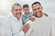 © Kirsten D/peopleimages.com - Happy, generations and portrait of family at beach for travel, relax and vacation. Bonding, smile and grandfather with dad and child in nature for seaside holiday, happiness and free time together