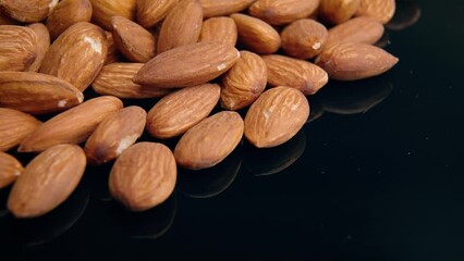 Wall Mural - Close-up view of many almonds placed on a black reflecting surface