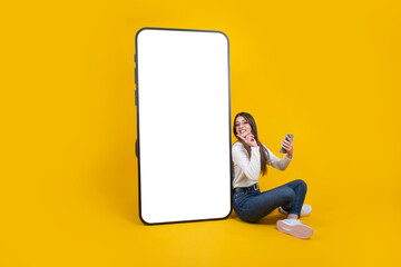 communication concept, cheerful woman leaning big smartphone with empty blank screen. huge mobile ph