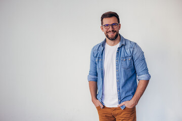 Wall Mural - Isolated shot of young handsome man with beard, wearing casual clothes, posing in studio on white background