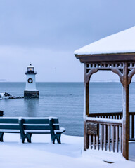 Sticker - a lighthouse and a bench are covered in snow and water