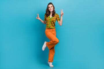 Sticker - Full size photo of satisfied cheerful woman dressed orange pants colorful cardigan showing v-sign isolated on blue color background