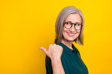 Sticker - Profile portrait of positive aged lady look indicate thumb finger empty space isolated on yellow color background