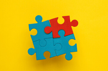 Wall Mural - Blue and red jigsaw puzzle pieces on a yellow background. Business concept