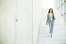 Young Business Woman Walking Down The Stairs And Holding Laptop
