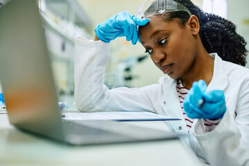 Wall Mural - pensive black biochemist analyzing research data while working in laboratory.