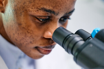 Wall Mural - close up of black female doctor looking through microscope.