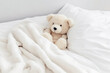 © Jim1786 - Cute little teddy bear lying sleeping alone on white bed in morning, generative ai.