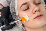 Fototapeta  - cosmetologist-dermatologist applies a facial gel peeling mask to the woman face. professional procedure in a beauty clinic salon for client. Skincare and cosmetology spa concept