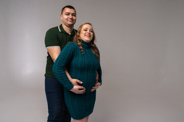 Canvas Print - Image of happy young man standing with his pregnant wife isolated on white wall background. Growing a family, expecting a child, a young family, emotions