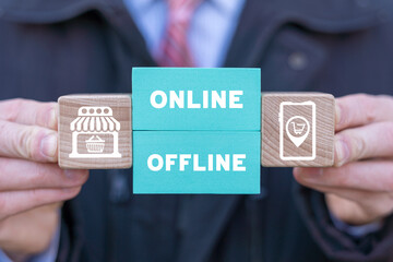 Man holding colorful blocks with icons and inscription: ONLINE OFFLINE. Transition from online to offline or vice versa in commerce, business, retail. Choose between online and offline.