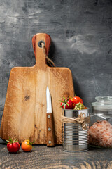 Wall Mural - cherry tomatoes in a tin and a cutting board on a dark wooden table against a gray wall. Space for text.